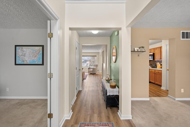 10335 Mackay Ct, Independence, KY 41051 - hallway featuring a textured ceiling, baseboards, light colored carpet, and light wood-style floors