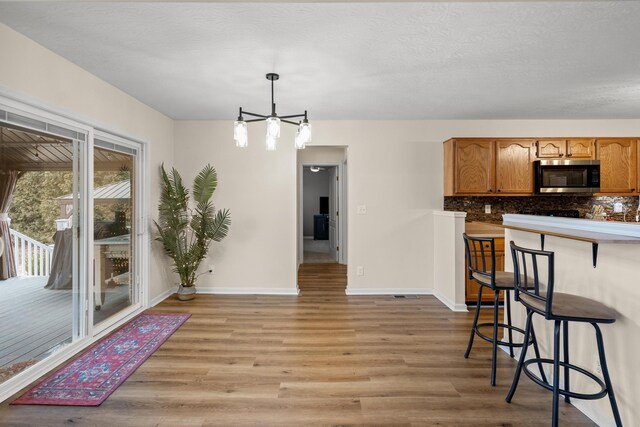 10335 Mackay Ct, Independence, KY 41051 - kitchen with stainless steel microwave, backsplash, light wood-style floors, and a kitchen bar