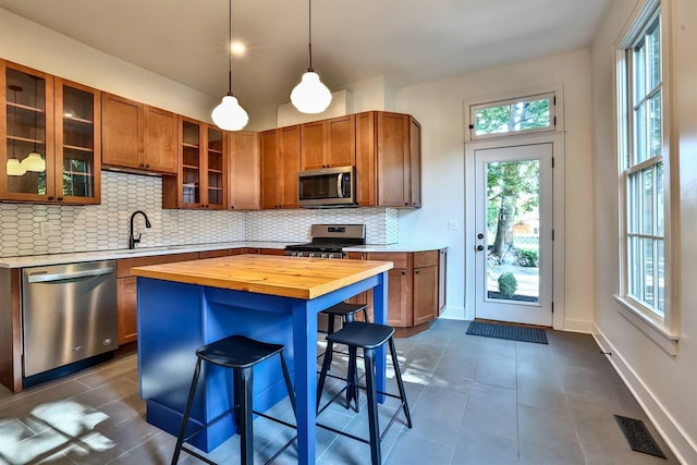 410 Emma St, Covington, KY 41011 - kitchen with appliances with stainless steel finishes, butcher block countertops, brown cabinetry, decorative backsplash, and dark tile patterned flooring