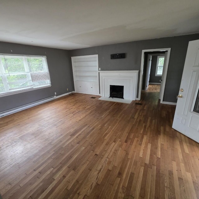 106 Roland Ave, Owenton, KY 40359 - unfurnished living room featuring dark wood-style flooring, a baseboard heating unit, plenty of natural light, and a fireplace with flush hearth