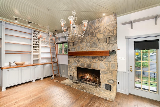 34 Ridge Rd, Fort Mitchell, KY 41011 - unfurnished living room with a chandelier, light wood finished floors, a stone fireplace, wood ceiling, and a wainscoted wall