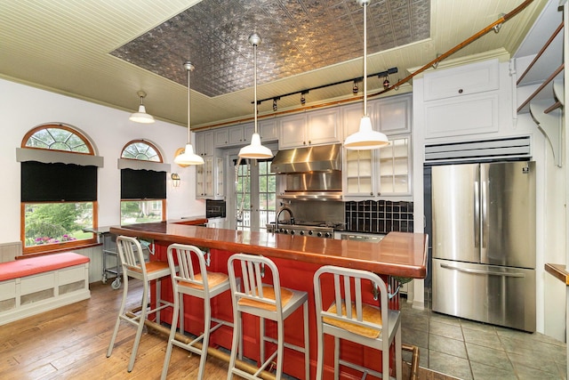 34 Ridge Rd, Fort Mitchell, KY 41011 - kitchen with freestanding refrigerator, dark countertops, under cabinet range hood, glass insert cabinets, and an island with sink