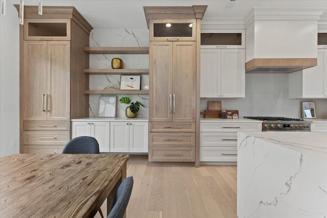 76 W 13th St Unit 34, Newport, KY 41071 - kitchen with open shelves, light wood-style flooring, premium range hood, glass insert cabinets, and light stone countertops