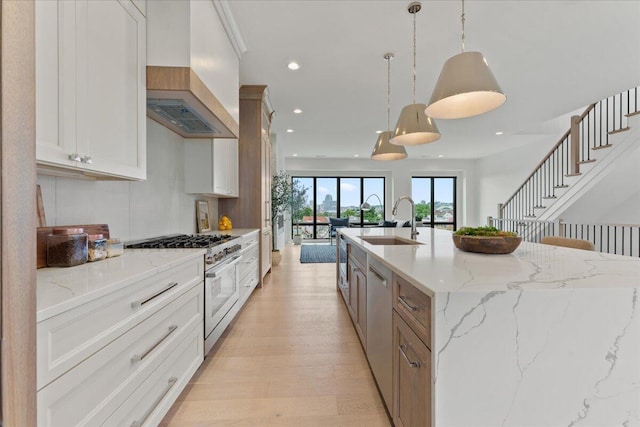 76 W 13th St Unit 34, Newport, KY 41071 - kitchen with appliances with stainless steel finishes, custom exhaust hood, light wood-style floors, recessed lighting, and pendant lighting