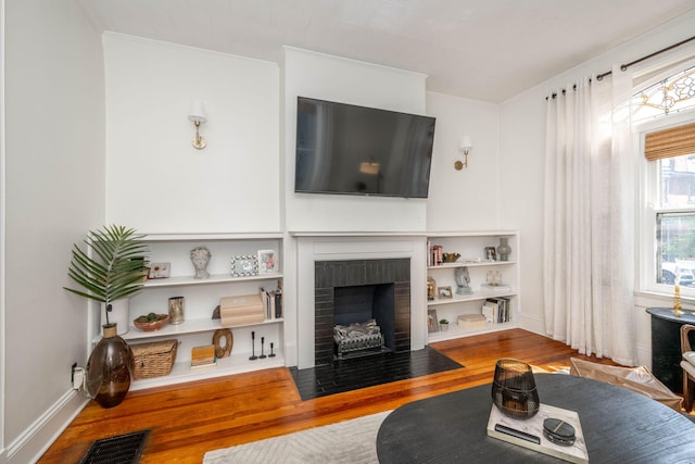 1915 Scott St, Covington, KY 41014 - living area featuring wood finished floors, a brick fireplace, built in shelves, and ornamental molding
