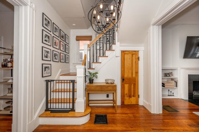 1915 Scott St, Covington, KY 41014 - stairs with hardwood / wood-style floors, a brick fireplace, and a chandelier