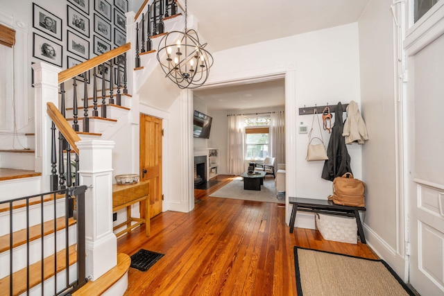1915 Scott St, Covington, KY 41014 - entrance foyer with stairway, wood-type flooring, a fireplace with flush hearth, and a chandelier