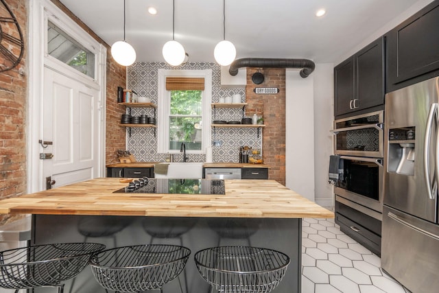 1915 Scott St, Covington, KY 41014 - kitchen featuring appliances with stainless steel finishes, butcher block counters, open shelves, a breakfast bar, and brick wall