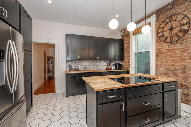 1915 Scott St, Covington, KY 41014 - kitchen featuring stainless steel refrigerator, wooden counters, black electric stovetop, brick wall, and hanging light fixtures
