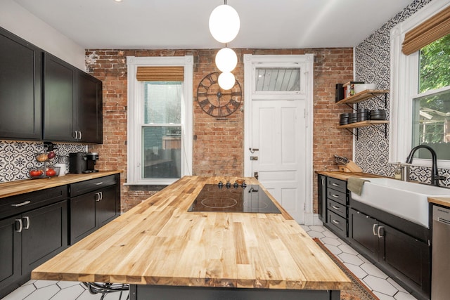 1915 Scott St, Covington, KY 41014 - kitchen featuring wood counters, black electric stovetop, tasteful backsplash, a center island, and brick wall
