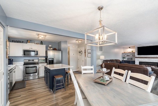 2246 Algiers St, Union, KY 41091 - dining area featuring wood finished floors, a chandelier, a textured ceiling, and a fireplace