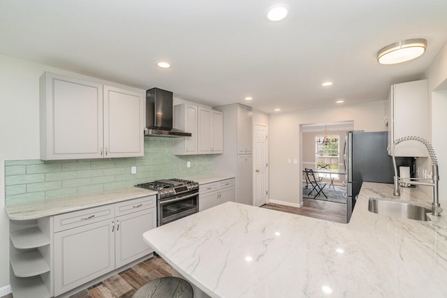 2282 Berkshire Ct, Florence, KY 41042 - kitchen featuring wall chimney exhaust hood, gas range, light wood-style flooring, tasteful backsplash, and a peninsula