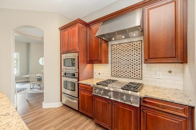 1217 Citation Dr, Union, KY 41091 - kitchen with appliances with stainless steel finishes, arched walkways, wall chimney range hood, a warming drawer, and light wood-type flooring