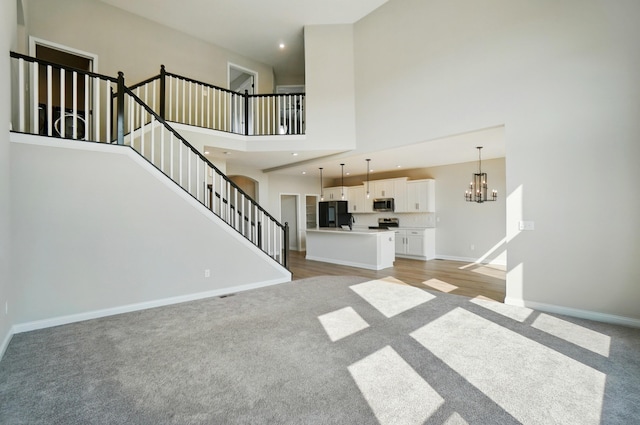3226 Chloe Ct, Hebron, KY 41048 - unfurnished living room featuring light colored carpet, stairway, a chandelier, a high ceiling, and recessed lighting