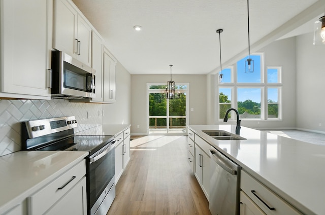 3226 Chloe Ct, Hebron, KY 41048 - kitchen featuring stainless steel appliances, light wood-style floors, decorative backsplash, light countertops, and decorative light fixtures
