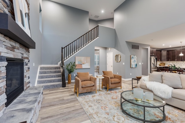 2320 Daybloom Ct, Hebron, KY 41048 - living room featuring a stone fireplace, stairway, light wood finished floors, a high ceiling, and recessed lighting