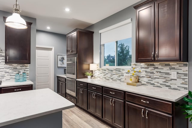2320 Daybloom Ct, Hebron, KY 41048 - kitchen with backsplash, dark brown cabinetry, double oven, light wood-style flooring, and hanging light fixtures
