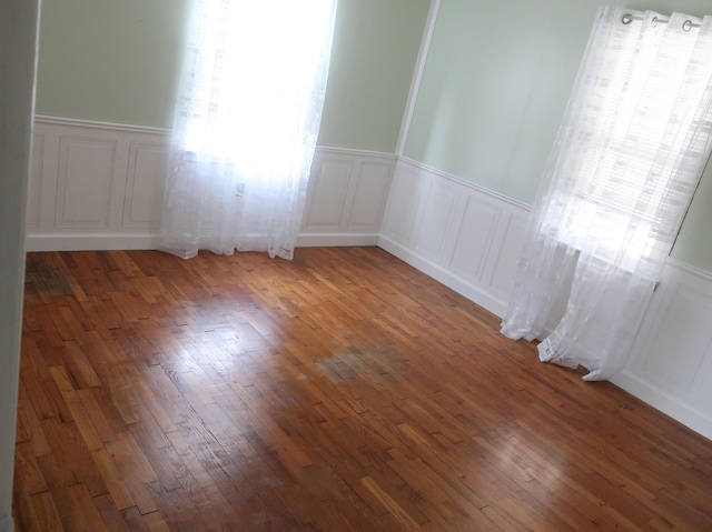 311 Elk Lake Rd, Owenton, KY 40359 - empty room with healthy amount of natural light, wainscoting, a decorative wall, and hardwood / wood-style flooring