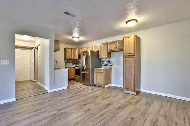 436 Marian Ln Unit 2, Florence, KY 41042 - kitchen featuring stainless steel appliances, light wood-type flooring, a textured ceiling, tasteful backsplash, and brown cabinets