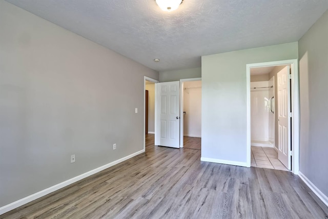 436 Marian Ln Unit 2, Florence, KY 41042 - unfurnished bedroom featuring wood finished floors, a textured ceiling, a closet, a spacious closet, and connected bathroom