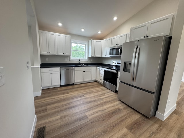 170 Saddlebrook Ln, Dry Ridge, KY 41035 - kitchen featuring appliances with stainless steel finishes, dark countertops, light wood finished floors, recessed lighting, and vaulted ceiling