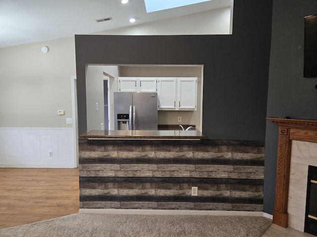 10 Meadow Ln Unit 9, Highland Heights, KY 41076 - kitchen featuring stainless steel fridge with ice dispenser, a skylight, white cabinetry, vaulted ceiling, and a wainscoted wall