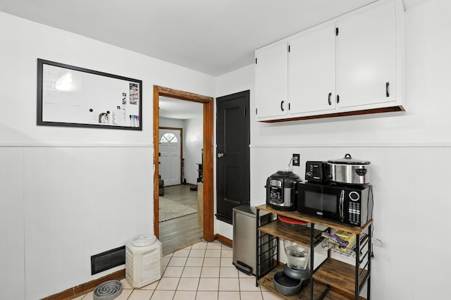 50 Russell St, Florence, KY 41042 - kitchen featuring white cabinetry, black microwave, wainscoting, and light tile patterned floors