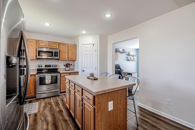 9128 Belvedere Ct, Florence, KY 41042 - kitchen with stainless steel appliances, a kitchen breakfast bar, dark wood-type flooring, tasteful backsplash, and a center island