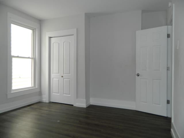 837 Central Ave, Newport, KY 41071 - unfurnished bedroom featuring dark wood-style flooring, multiple windows, and a closet