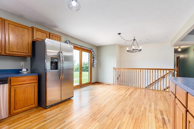 1041 Kidwell Rd, Demossville, KY 41033 - kitchen featuring stainless steel appliances, light wood-style floors, a chandelier, brown cabinetry, and hanging light fixtures