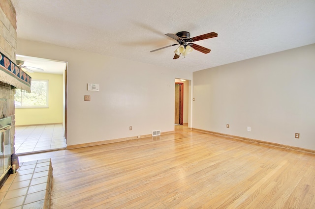 5370 Skyline Dr, Highland Heights, KY 41076 - empty room featuring ceiling fan, light wood-type flooring, a fireplace, and a textured ceiling