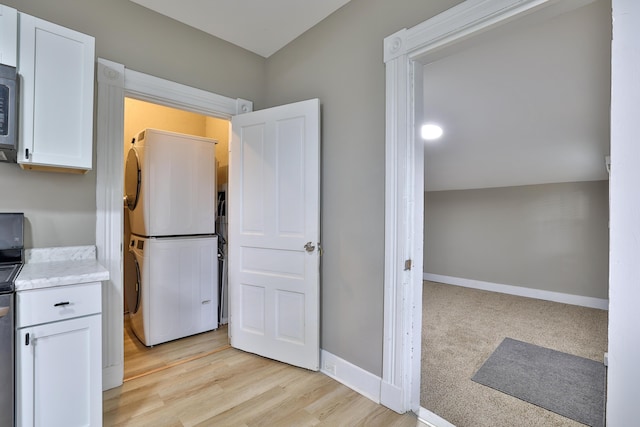1508 Holman Ave, Covington, KY 41011 - kitchen featuring stacked washer and clothes dryer, white cabinetry, stainless steel microwave, light wood-type flooring, and range