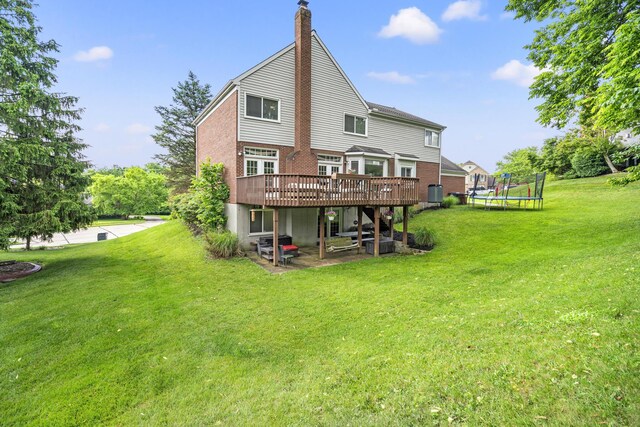 25 Regiment Ct, Wilder, KY 41076 - rear view of property featuring a trampoline, a deck, a chimney, brick siding, and a lawn
