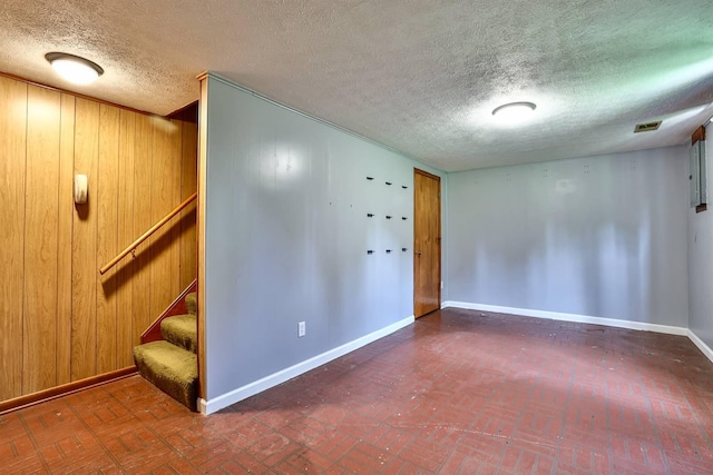 1710 Hilltop Dr, Carrollton, KY 41008 - empty room featuring a textured ceiling, stairway, wooden walls, and brick patterned flooring