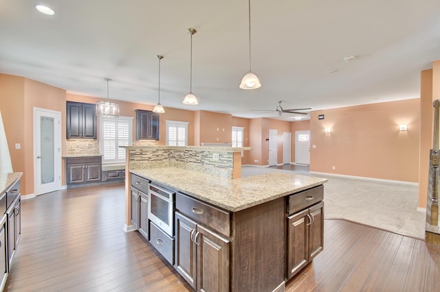740 Norbie Dr, Burlington, KY 41005 - kitchen with stainless steel microwave, a center island, ceiling fan, wood-type flooring, and backsplash