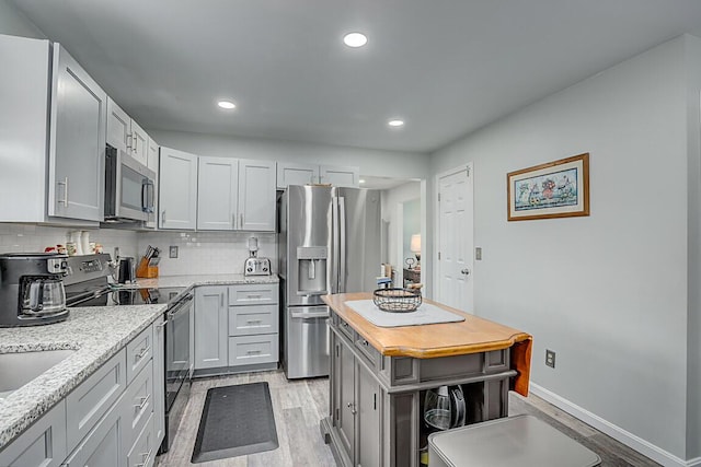 9070 Braxton Dr, Union, KY 41091 - kitchen featuring appliances with stainless steel finishes, light wood-style floors, decorative backsplash, recessed lighting, and light stone countertops
