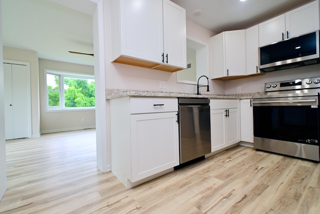 680 Manor Dr, Taylor Mill, KY 41015 - kitchen with stainless steel appliances, light wood-style flooring, white cabinetry, and light stone counters
