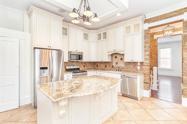 416 E 8th St, Newport, KY 41071 - kitchen featuring stainless steel appliances, a chandelier, a kitchen island, decorative backsplash, and light stone counters