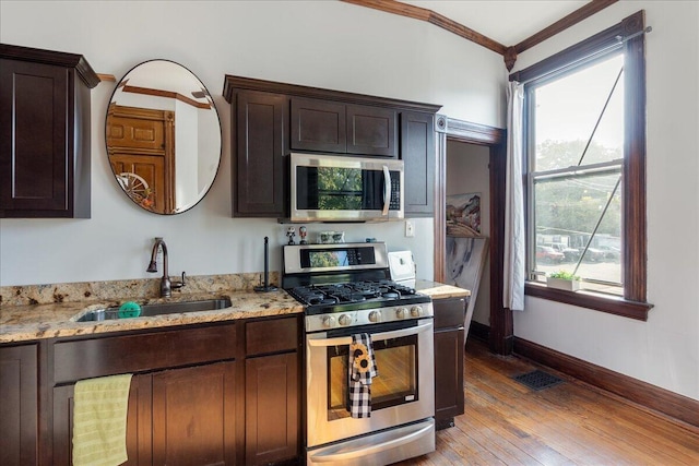411 E 10th St, Newport, KY 41071 - kitchen with appliances with stainless steel finishes, ornamental molding, light wood-style flooring, light stone countertops, and dark brown cabinets