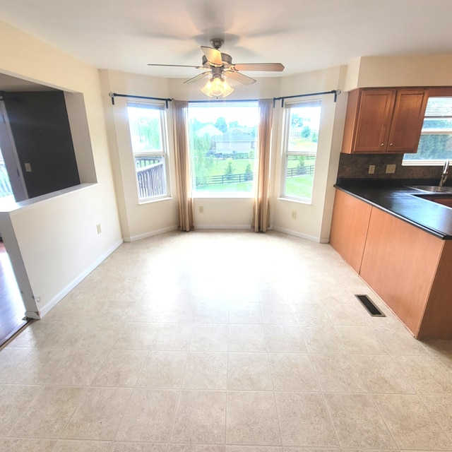 4467 Hackberry Ct, Burlington, KY 41005 - kitchen with dark countertops, a ceiling fan, backsplash, brown cabinets, and light tile patterned floors