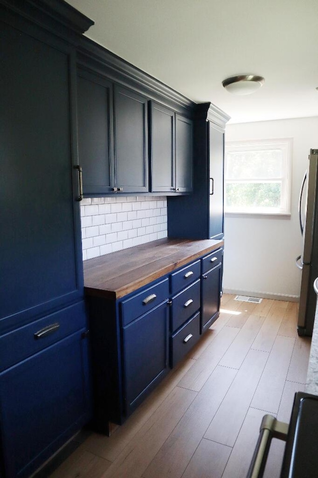 713 Ferncliffe Ave, Crescent Springs, KY 41017 - kitchen with butcher block countertops, freestanding refrigerator, backsplash, blue cabinets, and light wood-type flooring