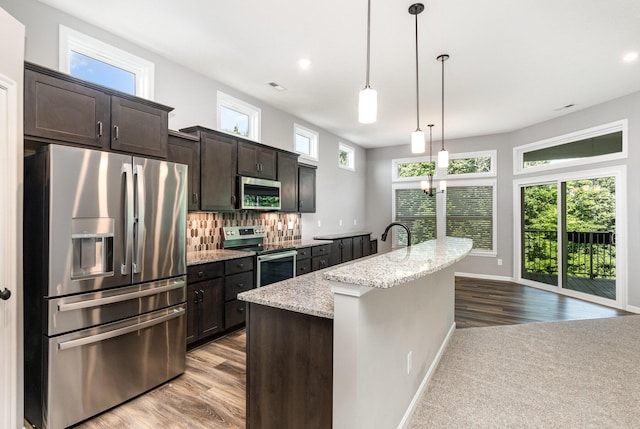 2175 Piazza Rdg, Covington, KY 41017 - kitchen with stainless steel appliances, dark brown cabinetry, a center island with sink, light stone countertops, and wood finished floors