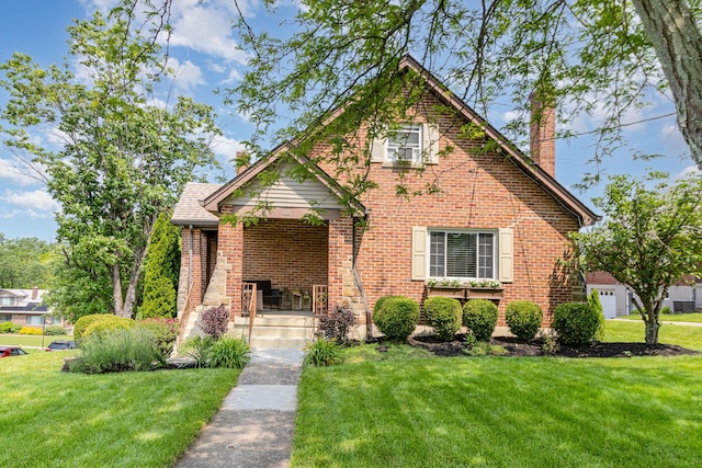 65 W Crittenden Ave, Fort Wright, KY 41011 - tudor-style house featuring a chimney, a front yard, and brick siding