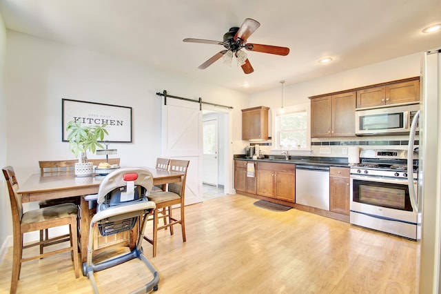 29 Crowell Ave, Fort Thomas, KY 41075 - kitchen with stainless steel appliances, dark countertops, a barn door, recessed lighting, and light wood-style flooring