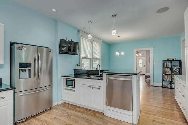3141 Beech Ave, Covington, KY 41015 - kitchen featuring stainless steel appliances, light wood finished floors, dark countertops, white cabinetry, and a chandelier