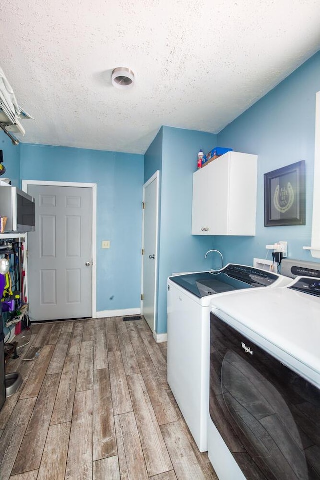 108 Regency Ct, Highland Heights, KY 41076 - laundry room with cabinet space, washer and dryer, light wood-style flooring, and a textured ceiling