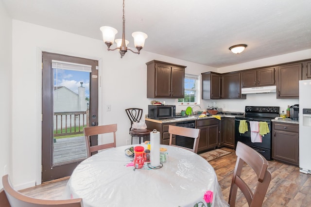 1539 Raintree Ct, Elsmere, KY 41018 - kitchen with black appliances, under cabinet range hood, dark brown cabinetry, light wood-style floors, and a chandelier