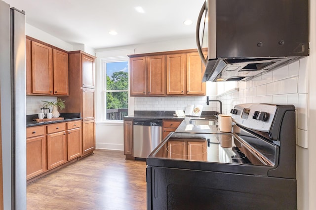 343 Rossford Ave, Fort Thomas, KY 41075 - kitchen featuring appliances with stainless steel finishes, dark countertops, light wood-type flooring, brown cabinets, and tasteful backsplash