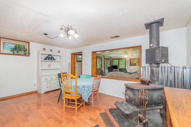 575 Sugar Creek Rd, Dry Ridge, KY 41035 - dining space featuring a wood stove, light wood finished floors, a textured ceiling, a ceiling fan, and a chandelier