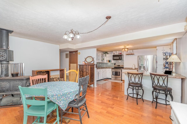 575 Sugar Creek Rd, Dry Ridge, KY 41035 - dining area with a wood stove, light wood finished floors, a textured ceiling, and a chandelier
